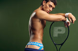 Model wearing the blue PUMP! Smash Jockstrap resting on a tennis racket
